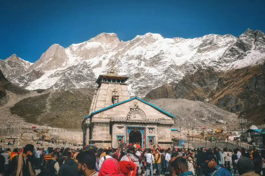 A crowd of pilgrims at Kedarnath Temple with snowcapped Himalayan peaks in the background Kedarnath