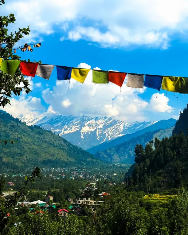 Charming view of Manali village with Himalayan mountains and colorful prayer flags in summer