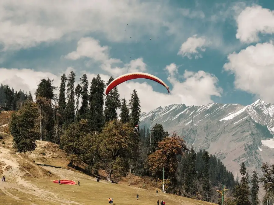 Thrilling paragliding above Manali's scenic landscape with majestic Himalayan mountains
